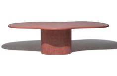 an oval wooden table with a pink top on a white background in the sun light