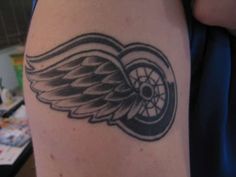 a person with a tattoo on their arm that has an angel wing and wheel design