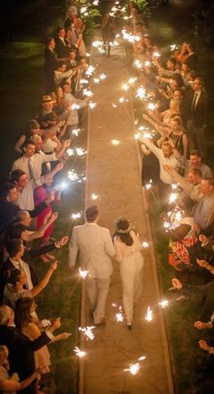 a bride and groom walking down the aisle holding sparklers