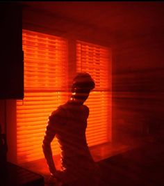 a man standing in front of a window covered in blinds