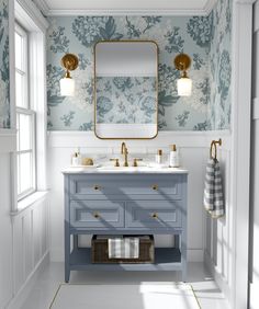 a bathroom with blue and white wallpaper, two sinks and a gold framed mirror