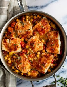 chicken and chickpeas stew in a skillet on a marble countertop with silverware