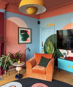 an orange chair sitting in front of a blue door with a painting on the wall