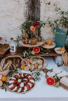 a table topped with lots of food next to a wall covered in vines and flowers