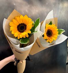 two sunflowers are wrapped in brown paper and placed on top of each other