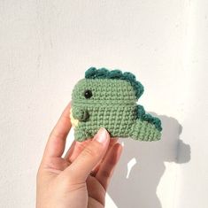 a hand holding a crocheted green stuffed animal