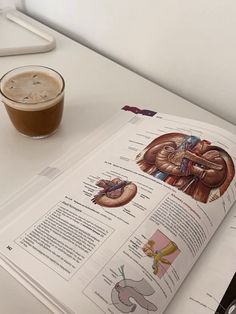 an open book sitting on top of a table next to a cup