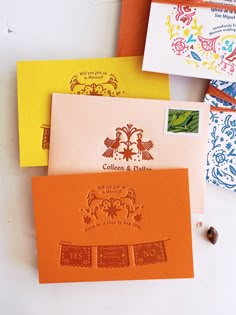 four different colored envelopes with stamps on them sitting next to each other and some type of stamp