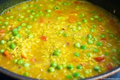 a pot filled with peas and carrots on top of a stove