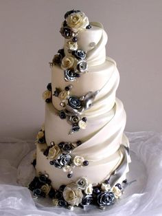 a three tiered wedding cake with white and black flowers on the top, sitting on a table