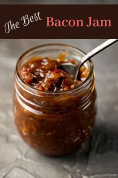 a spoon in a jar filled with food on top of a gray tablecloth covered surface