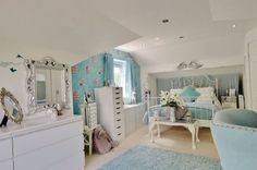 a bedroom with white furniture and blue wallpaper on the walls, along with a large mirror