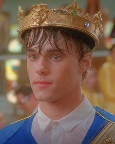 the young man is wearing a crown and smiling