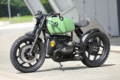 a green and black motorcycle parked on the side of a road next to a building