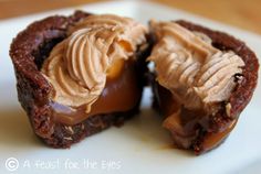 two pieces of chocolate cake with peanut butter frosting on top, sitting on a white plate