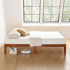 a bed sitting on top of a wooden floor next to a window