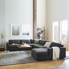 a living room with a sectional couch and coffee table in the middle, on top of a wooden floor