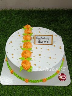 a birthday cake decorated with orange flowers on grass