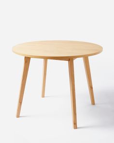 a round wooden table sitting on top of a white floor