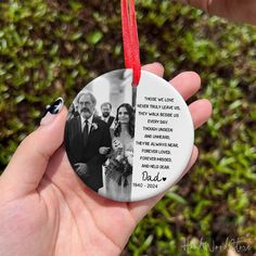 a hand holding a round ornament with an image of two men and a woman