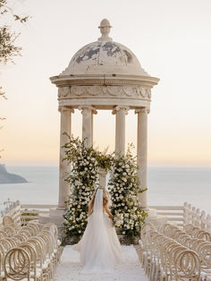 a bride and groom standing in front of an outdoor gazebo with flowers on it