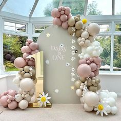 balloon arch with flowers and daisies in front of large window at entrance to room