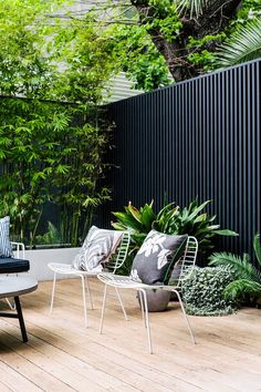 an outdoor patio with chairs, tables and potted plants on the decking area