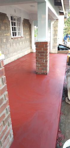 a house with red paint on the floor and brick pillars in front of it,