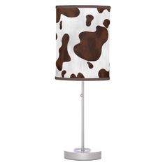 a cow print lamp shade on a metal base with a white and brown fabric covering