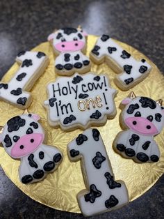 some decorated cookies are sitting on a plate with the words i'm one and two cows