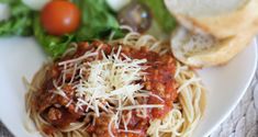 a white plate topped with spaghetti and bread