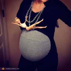 a pregnant woman wearing a necklace and holding her baby in the belly while standing next to a door