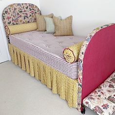 a pink bed with floral bedspread and pillows