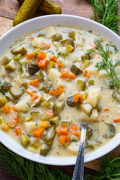 a white bowl filled with vegetable soup on top of a wooden table