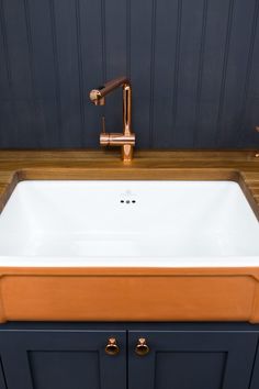 a white sink sitting under a faucet next to a wooden counter top in a bathroom