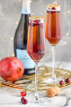 two wine glasses filled with liquid next to an apple and cheese slice on a gold tray