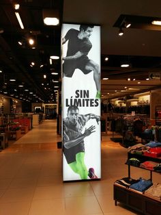 a large sign in the middle of a store with clothes on display and people walking by