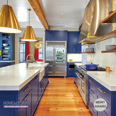 a large kitchen with blue cabinets and wood flooring is featured in the magazine homes & gardens