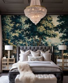 a large bed sitting under a chandelier next to a wall covered in trees