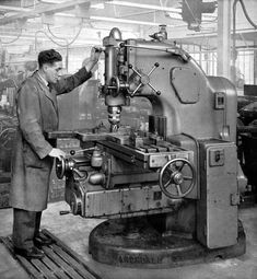 an old black and white photo of a man working on a machine