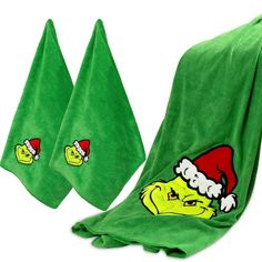 two green towels with the grin face on them, one has santa's hat