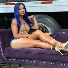 a woman sitting on top of a purple couch in front of a white semi truck