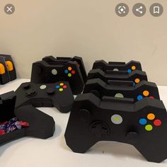 several black video game controllers sitting next to each other on a white counter top with colorful buttons