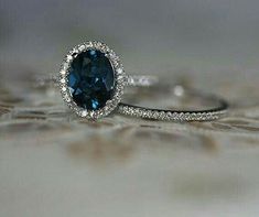 a blue diamond ring sitting on top of a piece of cloth with diamonds around it