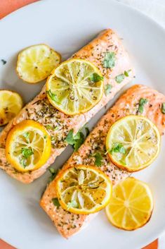 two salmon fillets on a plate with lemons