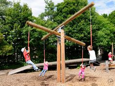 three children playing on a wooden swing set