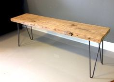 a wooden bench sitting on top of a white floor next to a wall with hairpin legs