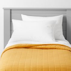 a bed with white pillows and yellow blanket