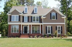 a large brown house with black shutters on the front and windows in the back