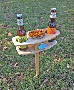 two beer bottles are sitting on a picnic table with snacks in front of them,